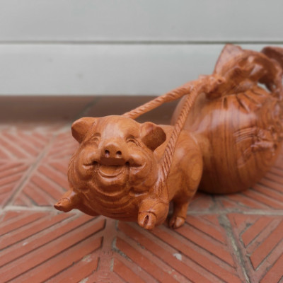 Tượng con heo kéo bao tiền bằng gỗ hương đá kt ngang 30cm